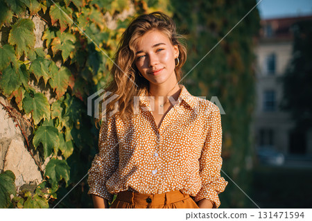 Young woman poses outdoors with sunshine illuminating her in a vibrant urban setting 131471594