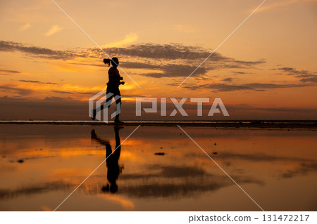 Silhouette of woman doing sports by the sea during an amazing sunset, jogging. Silhouette of woman doing sports by the sea during an amazing sunset, jogging. 131472217