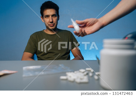 Narcotics transaction showing dealer presenting nasal spray near addicted client, surrounded by scattered pills, cash, plastic bag signaling substance abuse scenario. Concept of substance abuse. Narcotics transaction showing dealer presenting nasal spray near addicted client, surrounded by scattered pills, cash, plastic bag signaling substance abuse scenario. Concept of substance abuse. 131472463