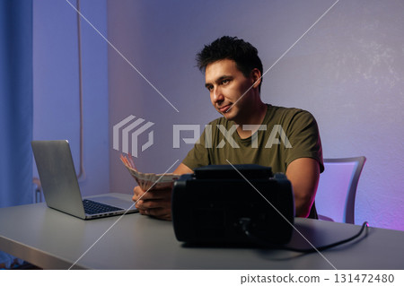Cashier counting Russian banknotes while working at desk with laptop and money counter machine, illustrating financial accounting in modern office environment. Concept of illegal cash withdrawal 131472480