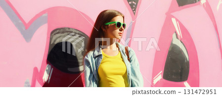 stylish young girl, modern teenager girl looking away posing against background of graffiti wall stylish young girl, modern teenager girl looking away posing against background of graffiti wall 131472951