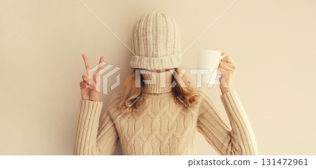 Happy funny young woman with cup of coffee drink in winter hat, sweater having fun on background 131472961