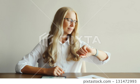 Confident mature woman professional working on digital tablet computer sitting at desk in office 131472993