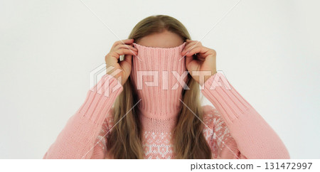 Funny young woman covering her face with knitted sweater or having fun standing on white background Funny young woman covering her face with knitted sweater or having fun standing on white background 131472997