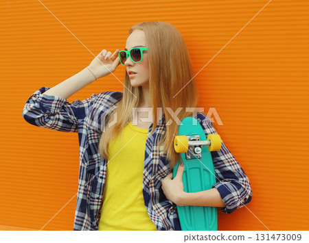 Stylish young woman with skateboard, modern teenage girl posing on city street 131473009