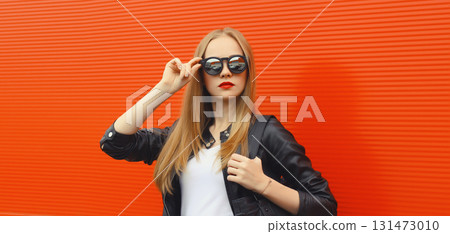 Stylish young woman standing in black leather jacket, sunglasses, modern blonde girl posing in city Stylish young woman standing in black leather jacket, sunglasses, modern blonde girl posing in city 131473010