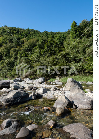 A river flowing through the blue sky and green mountains 131473371