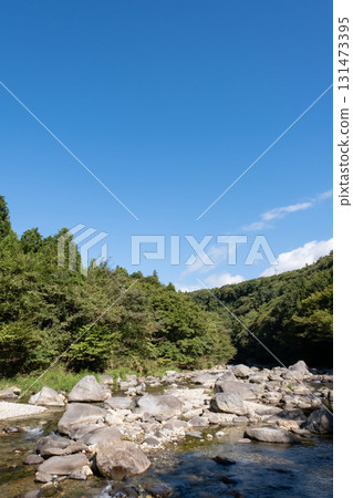 A river flowing through the blue sky and green mountains 131473395