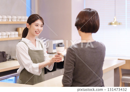 Cafe staff handing drinks to customers 131473432