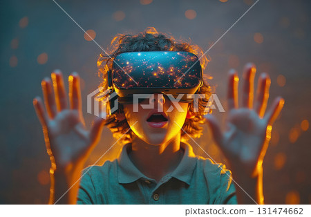 Boy wearing virtual reality headset with glowing digital projection, hand gestures control 131474662
