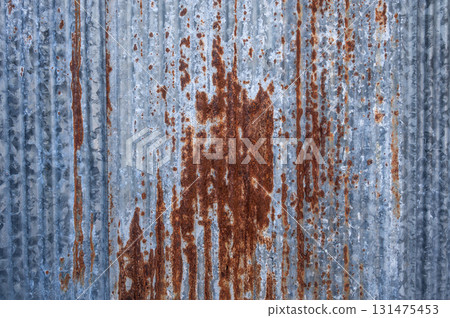 An old rusty metal sheet roof textured. Rust is an iron oxide formed by the reaction of iron and oxygen in the catalytic presence of water or air moisture. 131475453