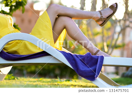 Young woman relaxing outdoors on sunny summer day. Happy lady lying down on comfortable beach chair daydreaming thinking. Calm beautiful smiling girl enjoying fresh air relaxing with closed eyes. Young woman relaxing outdoors on sunny summer day. Happy lady lying down on comfortable beach chair daydreaming thinking. Calm beautiful smiling girl enjoying fresh air relaxing with closed eyes. 131475701