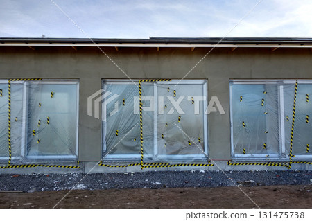 Windows of a house under construction covered with protective plastic film. 131475738