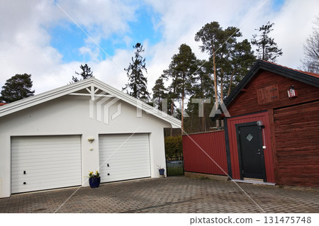 White new garage for two cars and wooden barn on private house yard. White new garage for two cars and wooden barn on private house yard. 131475748