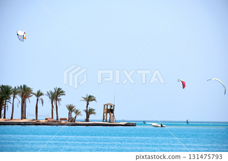 Tropical sea pier with palms and recreational zone, tourists windsurfing and kite surfing. Summer exotic vacations 131475793