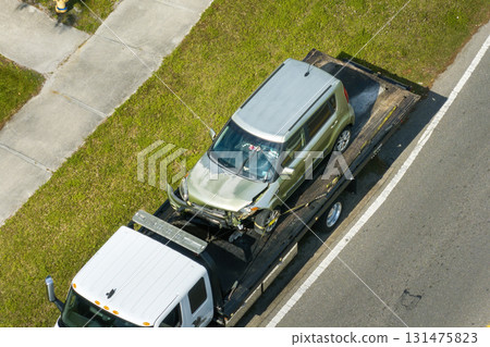 Tow truck loading crashed car on accident site. Emergency services personnel and vehicles responding to vehicle crash on American street 131475823