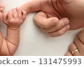 Close-up little hand of child and palm of mother and father. The newborn baby has a firm grip on the parent's finger after birth. A newborn holds on to mom's, dad's finger.  131475993