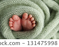 Soft feet of a newborn in a olive green blanket. Close up of toes, heels and feet of a newborn baby. 131475998