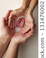 A father and mother hold the feet of a newborn child in a white blanket on a white background.. The feet of a newborn in the hands of parents. Photo of foot, heels and toes.The palms of the parents. 131476002