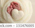 Soft feet of a new born in a white wool blanket. Close up of toes, heels and feet of a newborn. Knitted white heart in the legs of a baby. Macro photography.The tiny foot of a newborn baby 131476005