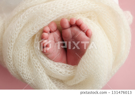Close up of toes, heels and feet of a newborn baby.The tiny foot of a newborn. Soft feet of a newborn in a white blanket, pink background. Close up of toes, heels and feet of a newborn baby.The tiny foot of a newborn. Soft feet of a newborn in a white blanket, pink background. 131476013