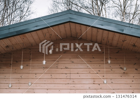 hanging glass lights add charm to wooden cabin under cloudy sky in woods during fall season. closeup 131476314