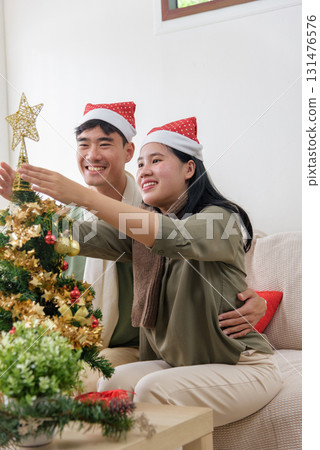 Christmas winter holiday brings joy, happy couple love decorating tree with golden star, festive celebration at cozy home, smiling faces share warm christmas spirit. Christmas winter holiday brings joy, happy couple love decorating tree with golden star, festive celebration at cozy home, smiling faces share warm christmas spirit. 131476576