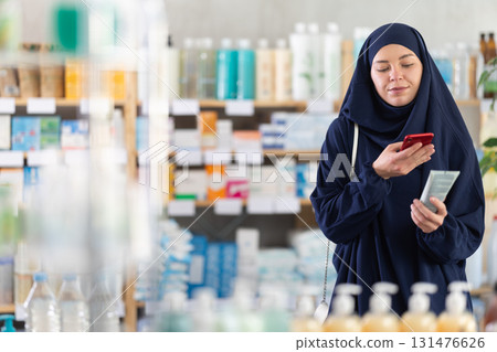 Muslim woman scanning body lotion with smartphone 131476626