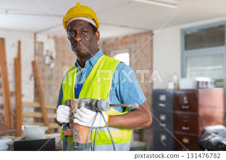 African american contractor standing with chipping chisel at construction site African american contractor standing with chipping chisel at construction site 131476782