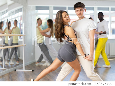 Positive guy dancing playful bachata with girl during group class 131476790
