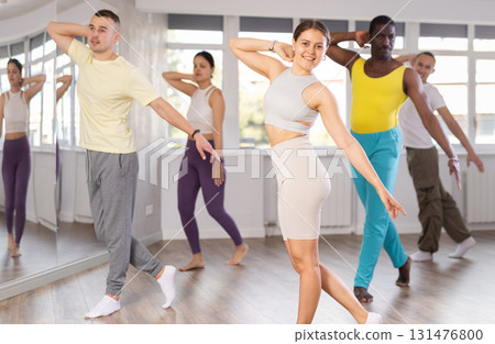 Beaming young girl leading group Latin dance class 131476800