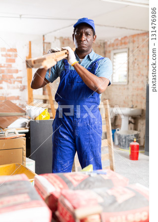 African american builder arranging timber in building under renovation 131476986