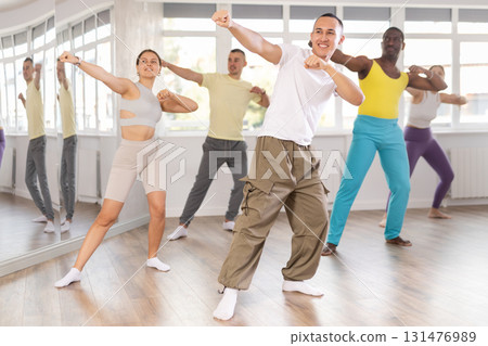 Young Asian male instructor guiding group through zumba routine 131476989