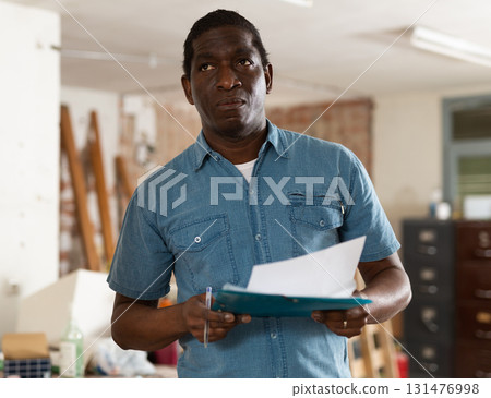 Focused African American man with papers planning home renovation Focused African American man with papers planning home renovation 131476998