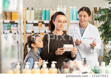 Woman with daughter choosing medication while pharmacist offering options Woman with daughter choosing medication while pharmacist offering options 131477051