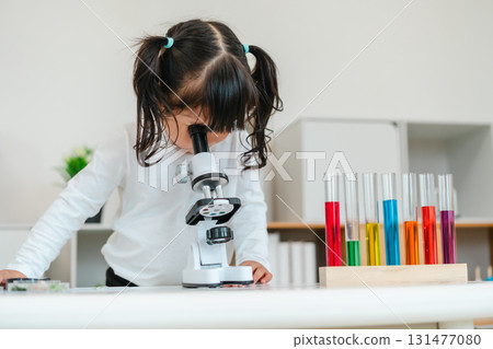 toddler girl scientist looking through microscope. learning science toddler girl scientist looking through microscope. learning science 131477080