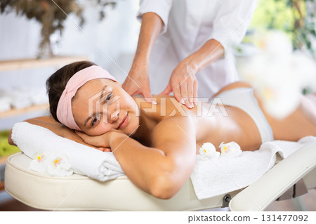 Female masseur works out shoulder and back problem area for female athlete client. Close-up Female masseur works out shoulder and back problem area for female athlete client. Close-up 131477092