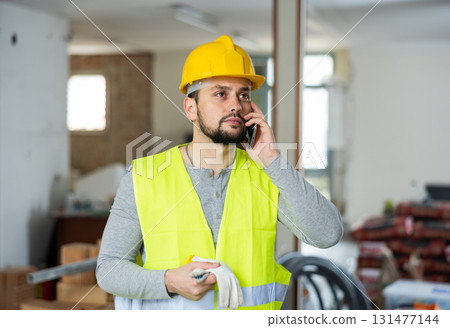 Builder is talking on a mobile phone Builder is talking on a mobile phone 131477144