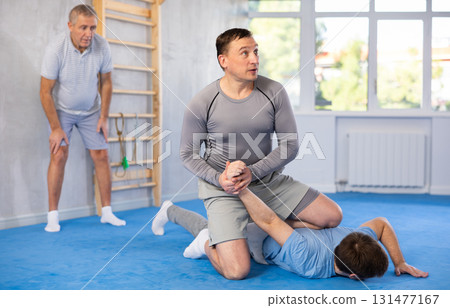 Man practicing painful armlock on male opponent at self defence training 131477167