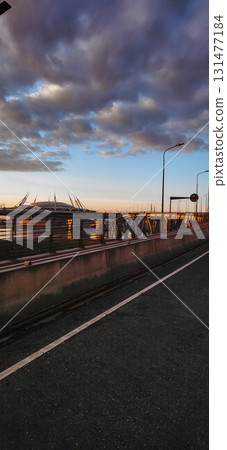 Scenic view of a bridge bathed in golden sunset light, highlighting the pathway designed for cyclists. The tranquil setting reflects a peaceful evening mood with clear skies 131477184