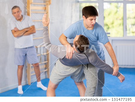Two athlete men of different age in sportswear practicing self-defense sparring in hall Two athlete men of different age in sportswear practicing self-defense sparring in hall 131477195