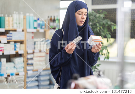 Young Muslim woman customer choosing pills in box in drugstore Young Muslim woman customer choosing pills in box in drugstore 131477213