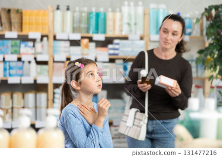 child stands and coughs in the pharmacy, and the mother chooses medications child stands and coughs in the pharmacy, and the mother chooses medications 131477216