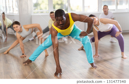 African man with team of like-minded multinational people learn to elements of contemporary dance 131477340