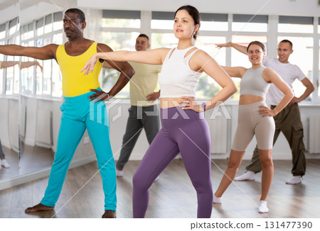 Young Asian woman practicing vigorous zumba with group Young Asian woman practicing vigorous zumba with group 131477390