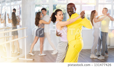 Middle-aged man and woman practicing waltz dance in pair in training hall Middle-aged man and woman practicing waltz dance in pair in training hall 131477426