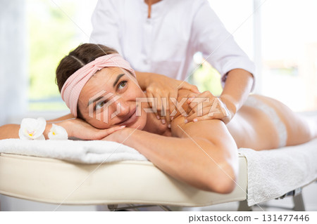 Female masseur works out shoulder and back problem area for female athlete client. Close-up Female masseur works out shoulder and back problem area for female athlete client. Close-up 131477446