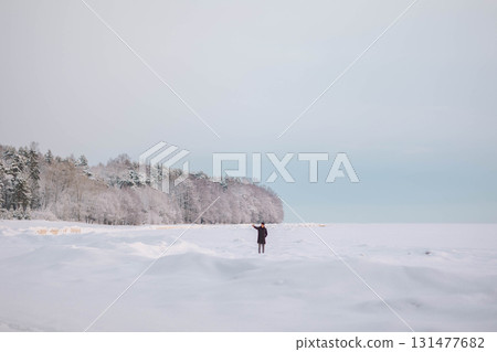 Beautiful winter landscape in minimalist style. Small figures of people on field of white snow and forest on horizon. Light and airy feel and light color palette. Beautiful winter landscape in minimalist style. Small figures of people on field of white snow and forest on horizon. Light and airy feel and light color palette. 131477682
