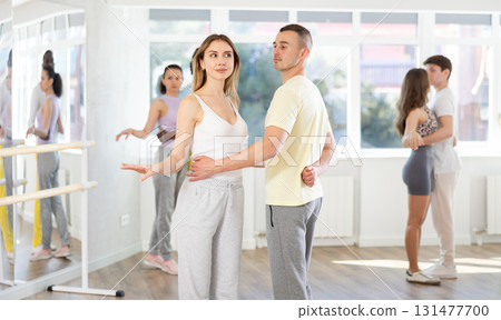 Young girl and guy in sportswear dancing together with group of multinational people slow ballroom dances in pairs in ball room at dance salon Young girl and guy in sportswear dancing together with group of multinational people slow ballroom dances in pairs in ball room at dance salon 131477700