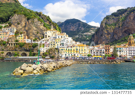 Panoramic view, aerial skyline of small haven of Amalfi village with tiny beach and colorful houses located on rock. Tops of mountains on Amalfi coast, Salerno, Campania, Italy. Panoramic view, aerial skyline of small haven of Amalfi village with tiny beach and colorful houses located on rock. Tops of mountains on Amalfi coast, Salerno, Campania, Italy. 131477735